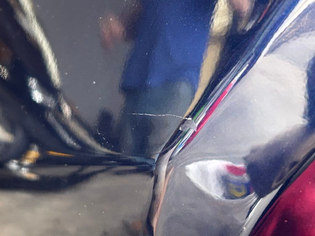 Close up of a car's blue paint, showing a deep scratch and paint chip.