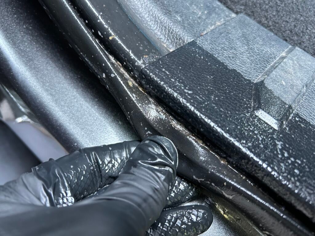 Close-up image of a vehicle's door jam seal. The seal is dirty and exposed.